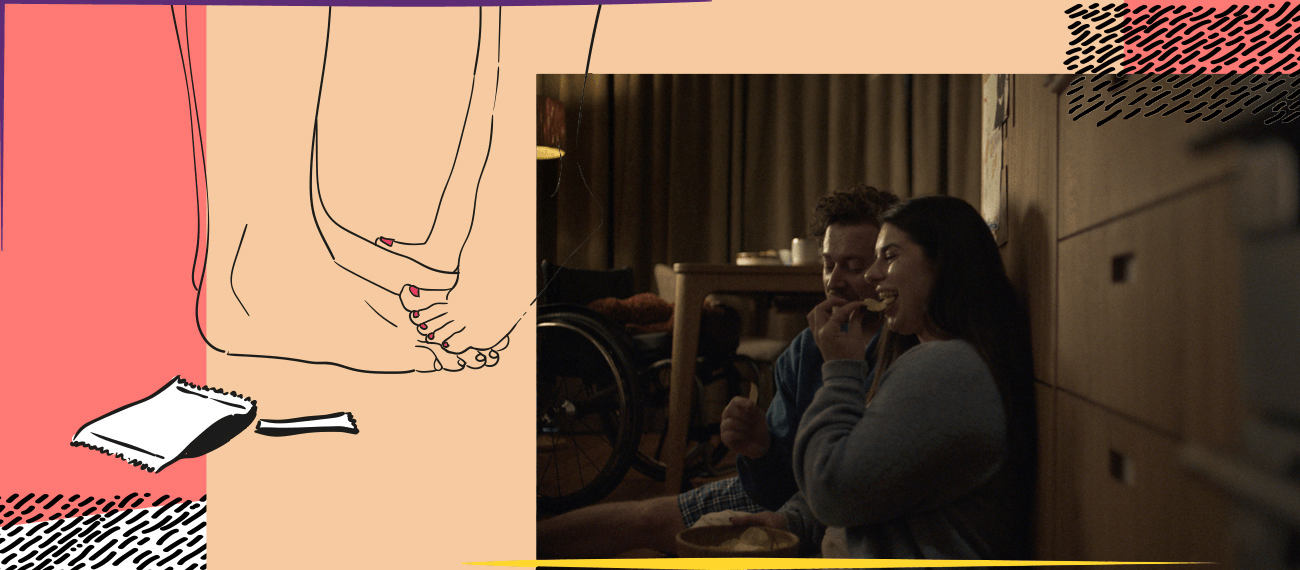 Couple eating chips sitting on the floor and leaning against a cupboard